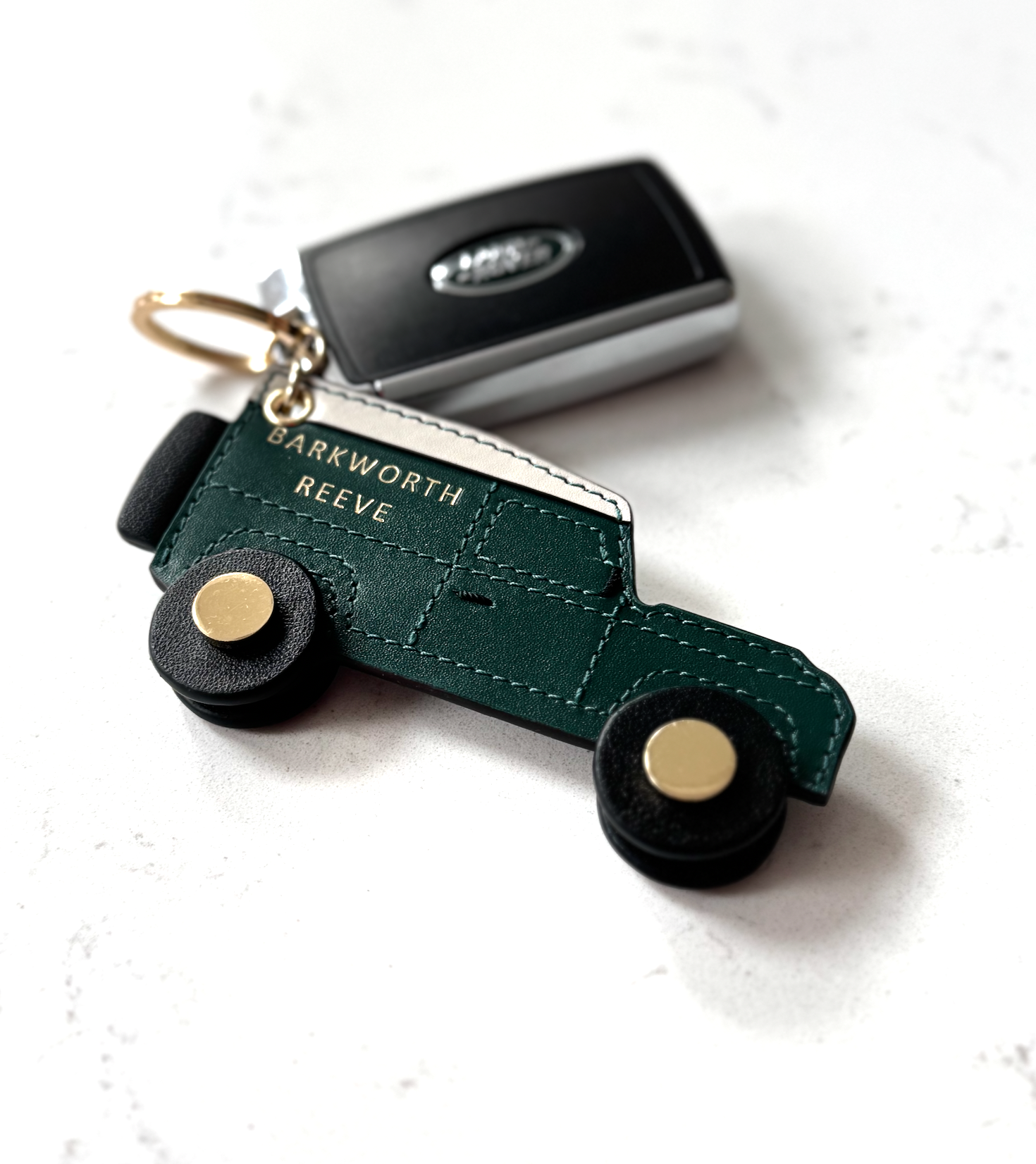 Green leather 4x4 off road keyring with black rotating wheels and keys on marble worktop
