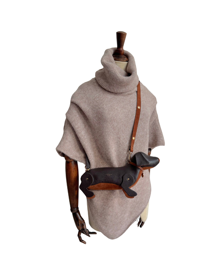 mannequin wearing oat marl poncho with roll neck wearing a cross body Chocolate Leather sausage dog handbag with leather strap