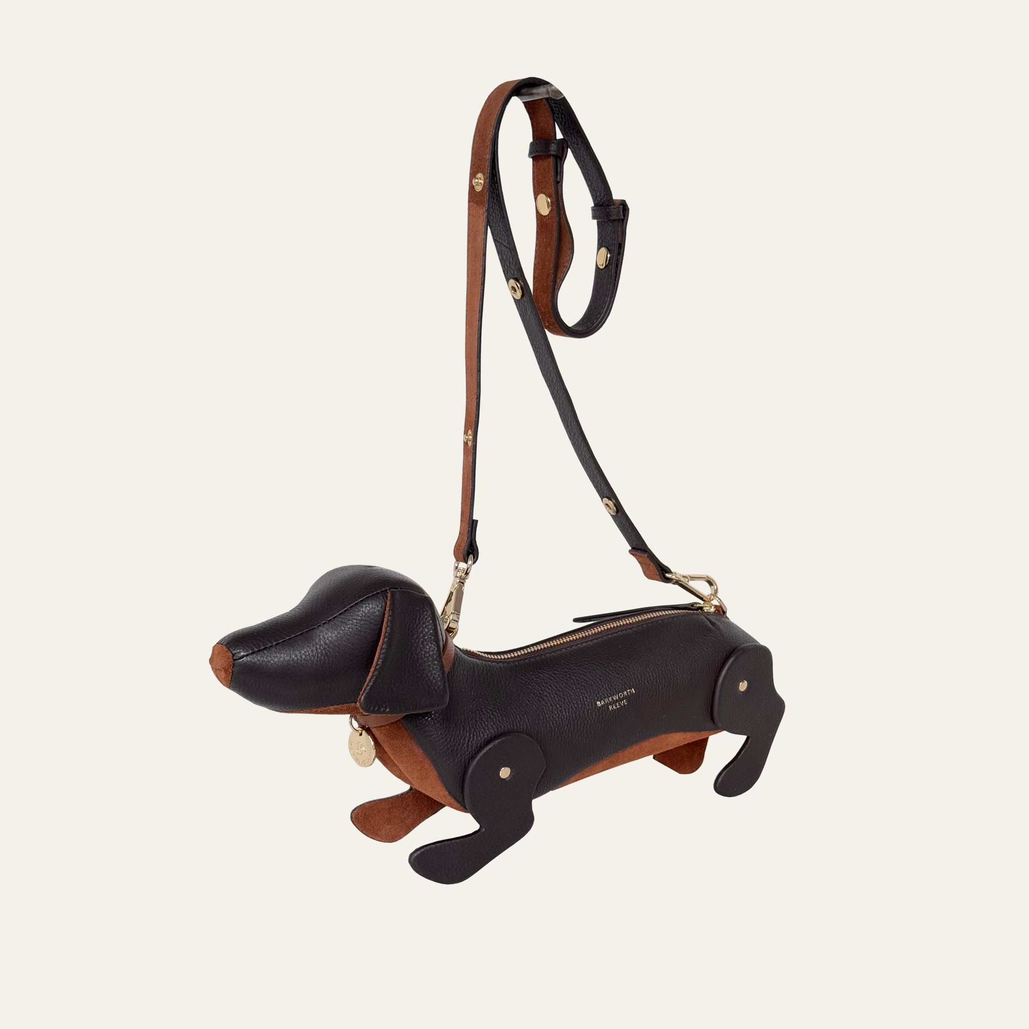 Leather sasuage dog handbag with adjustable shoulder strap. handbag is choclate brown leather with a tan suede tummy and a brass zip opening on the back of the dog.