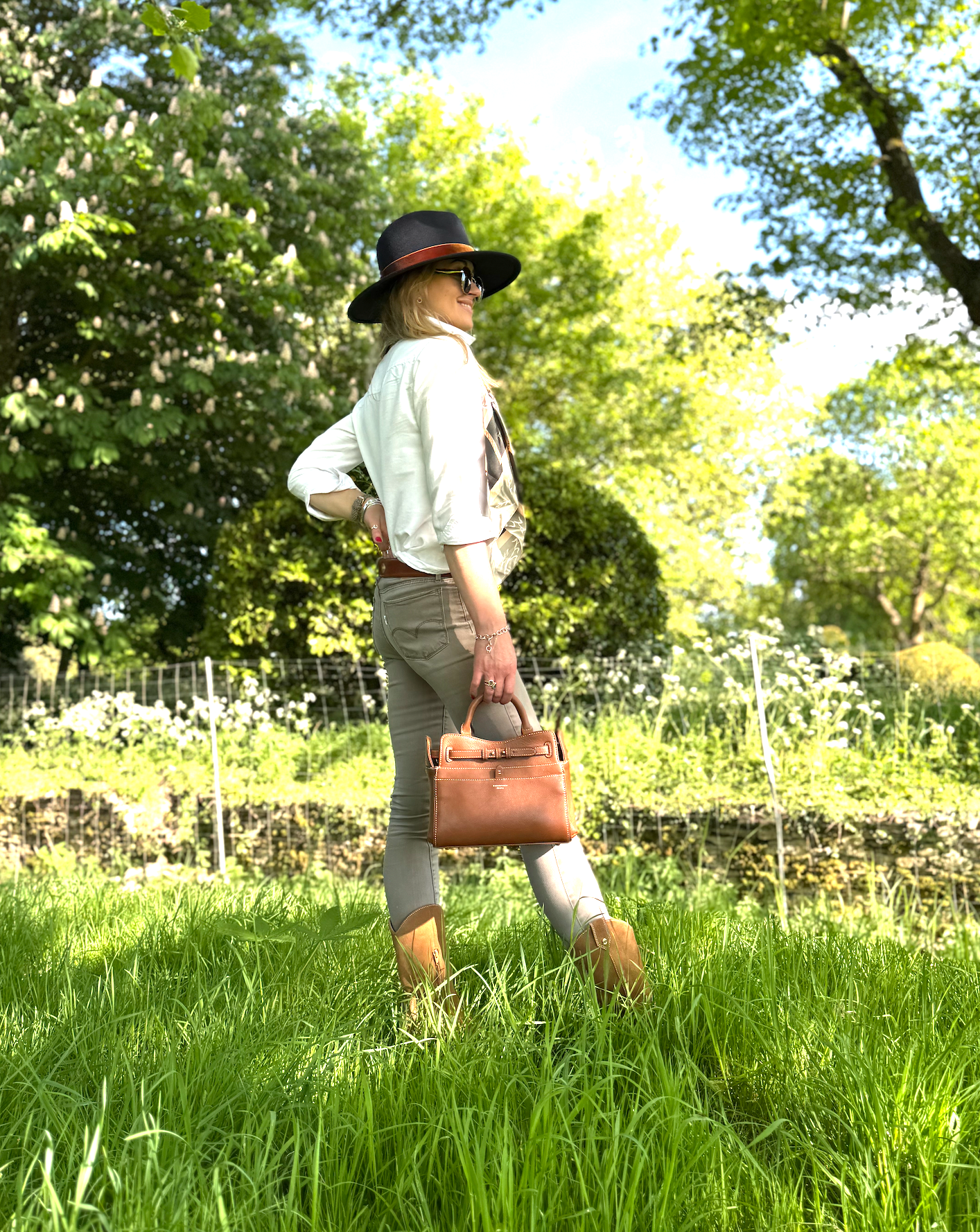 Barkworth Reeve tan ambridge bag in sunshine field held by a girl in a hat