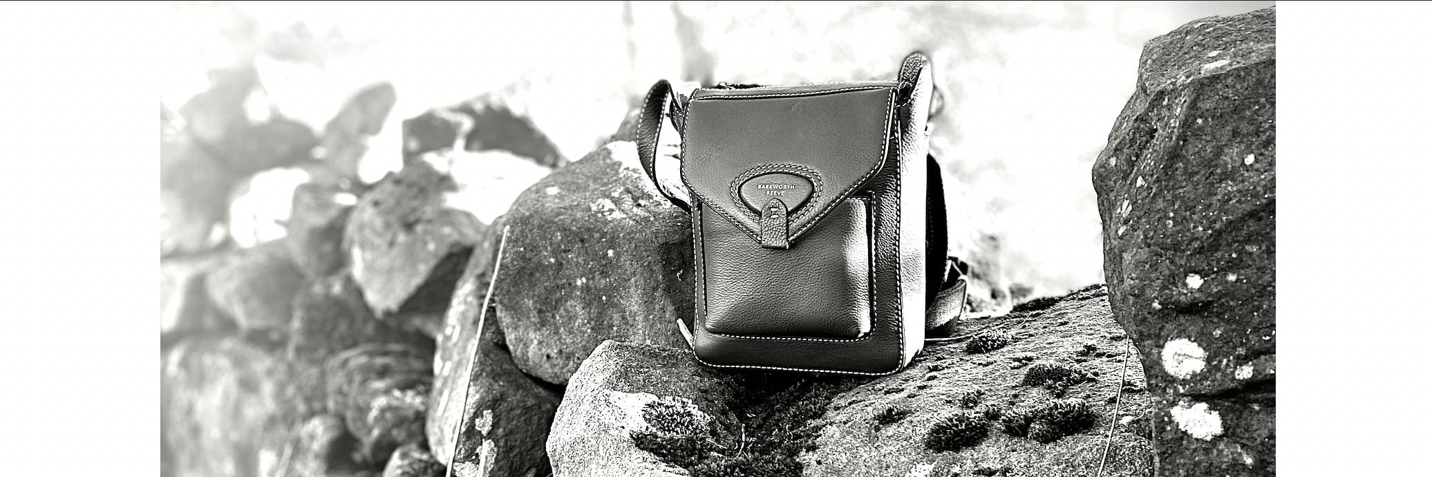 barkworth reeve cross body leather hackthorn bag in black and white on a dry stone wall in the countryside