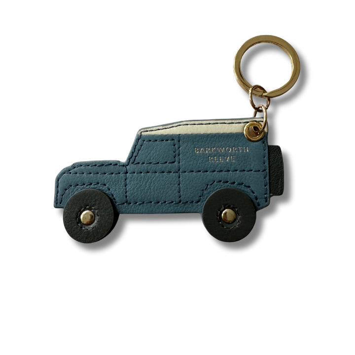Blue off road car-shaped keychain with gold accents on a white background and black wheels.  stitch detail 