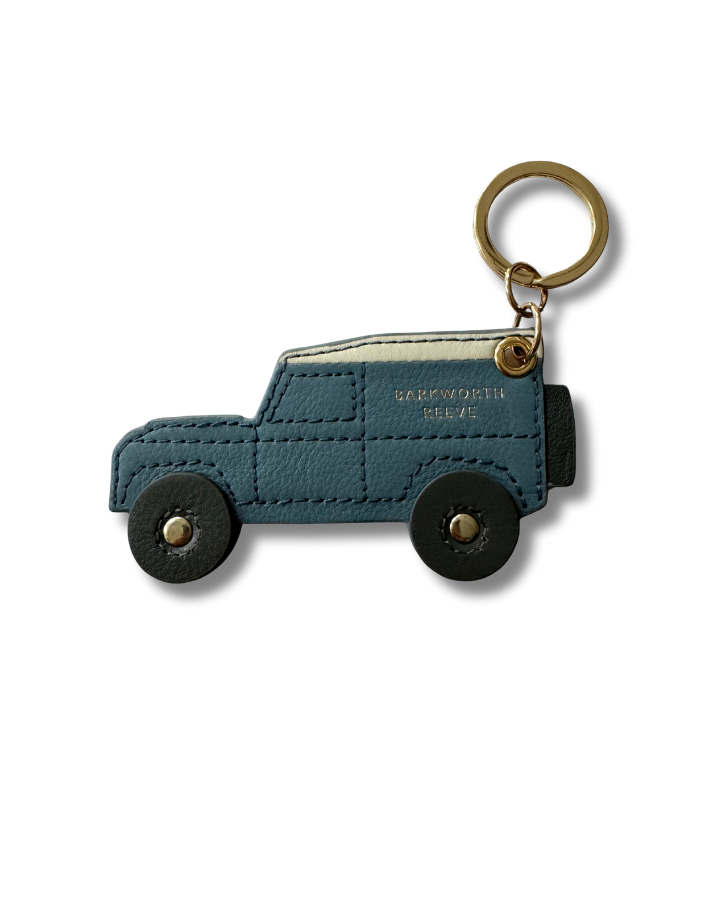 Blue off road car-shaped keychain with gold accents on a white background and black wheels.  stitch detail 