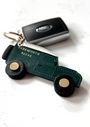 Green leather 4x4 off road keyring with black rotating wheels and keys on marble worktop