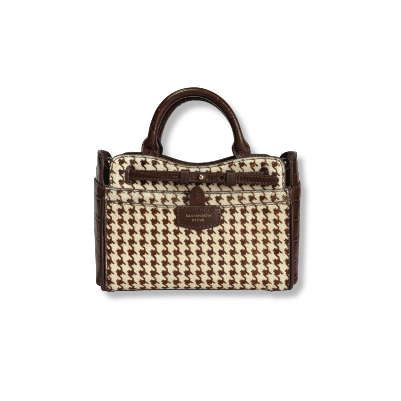 A structured handbag with a brown and beige houndstooth pattern, dark brown leather trim, a top handle, and a central hanging strap detail, shown against a plain white background.