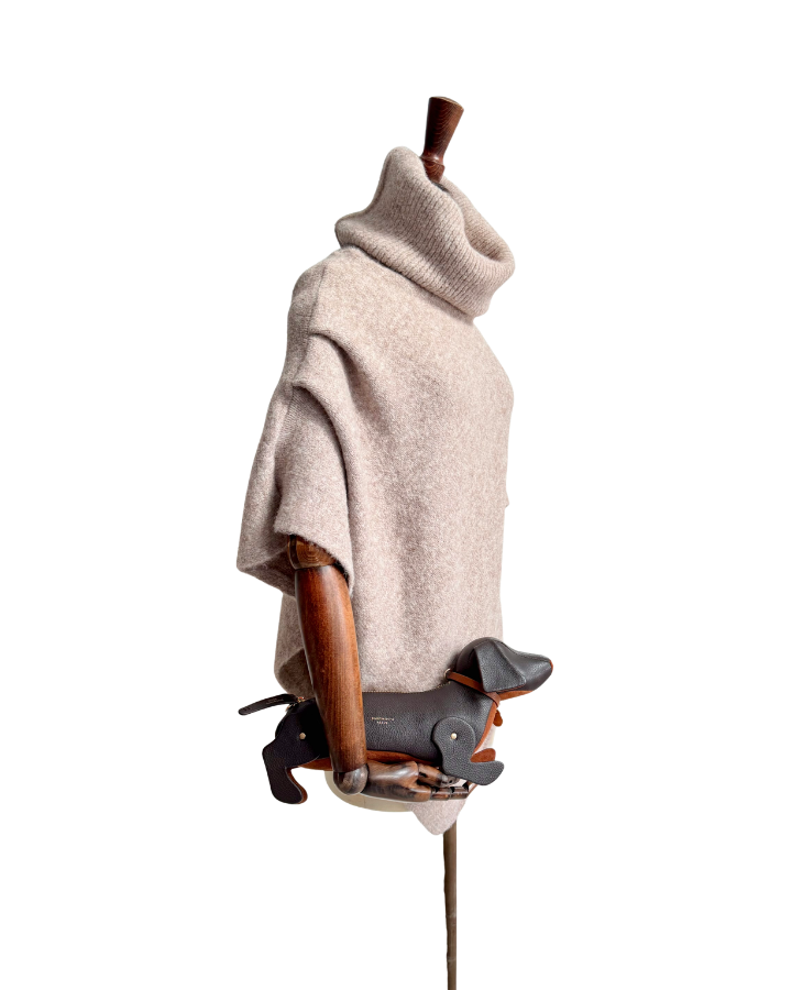mannequin with oat marl poncho holding Chocolate Leather sausage dog handbag