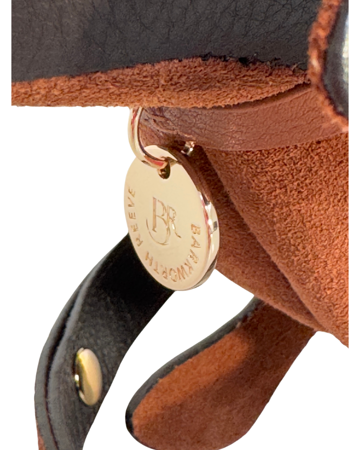 Close-up of a leather product with a gold tag featuring a logo and text.