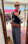 Person taking a mirror selfie wearing sunglasses and a white shirt with a patterned background.