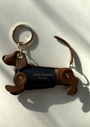 tan leather dachshund keyring, with blue leather coat and gold keyring split ring on a shadow background