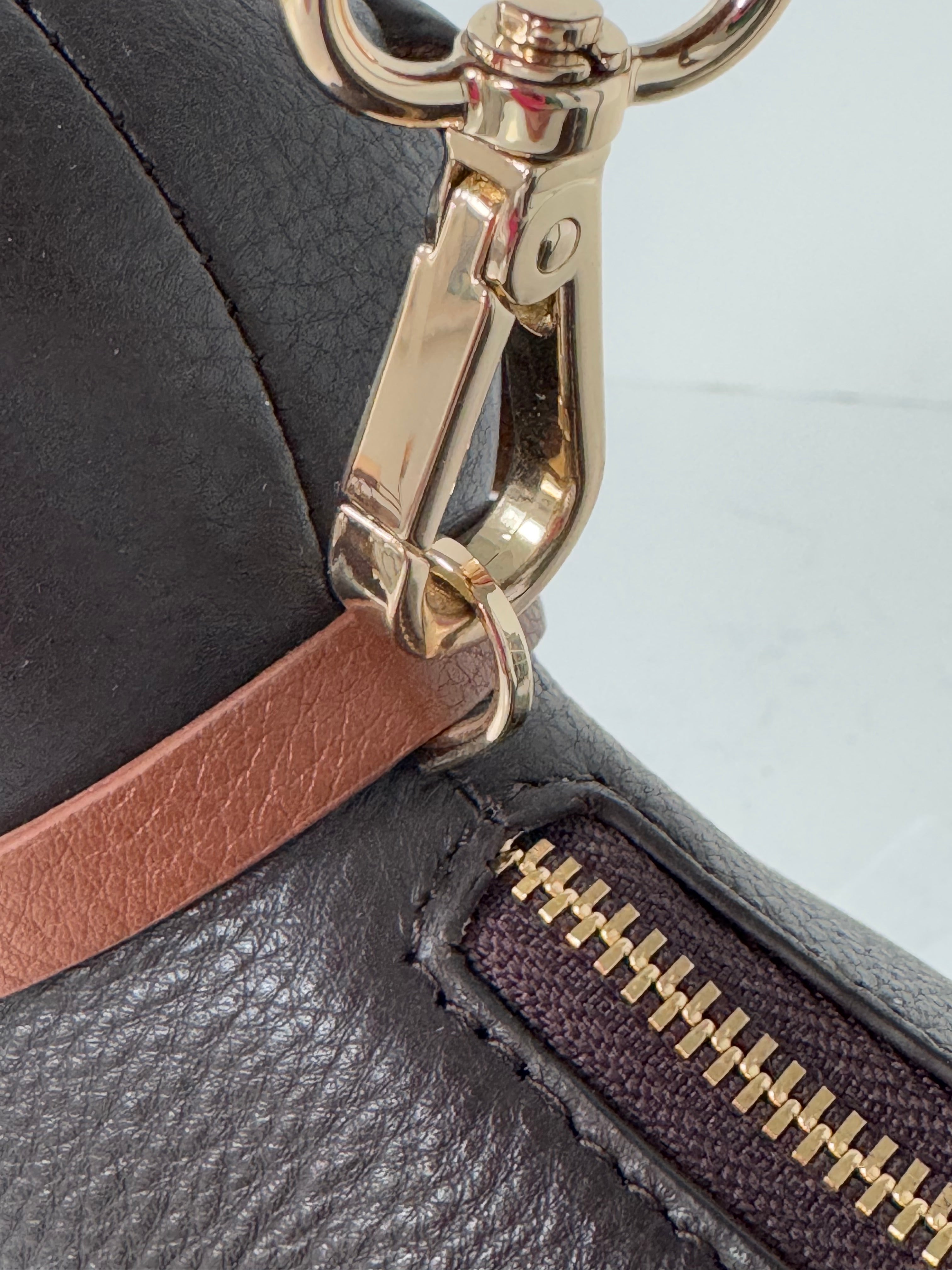 Leather sasuage dog handbag with adjustable shoulder strap. zoomed in image of the attachment for the strap on collar
