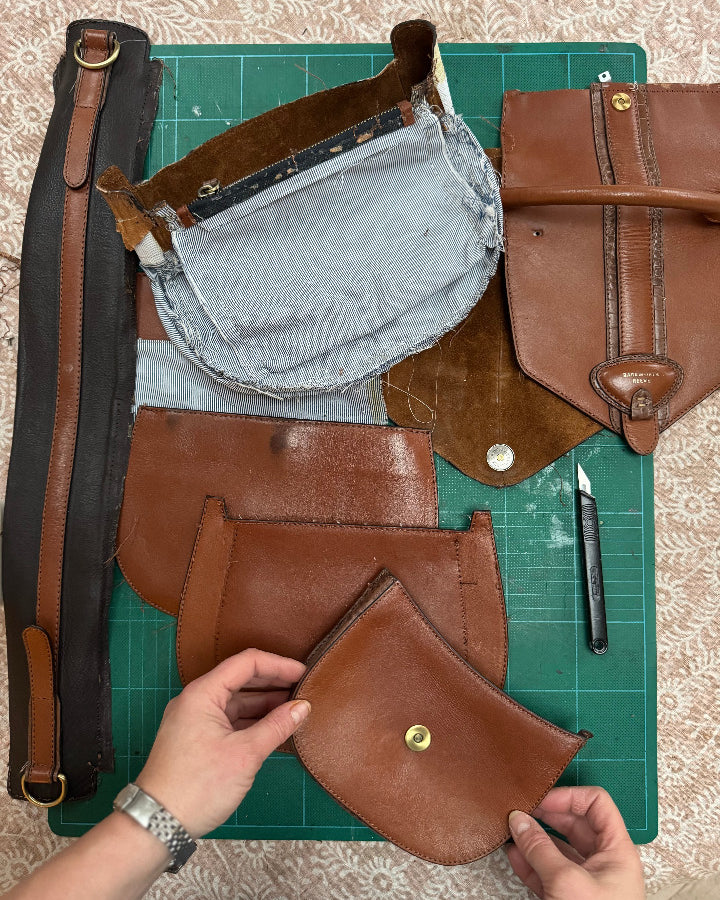 Brown leather bag being assembled on a green cutting mat with tools.