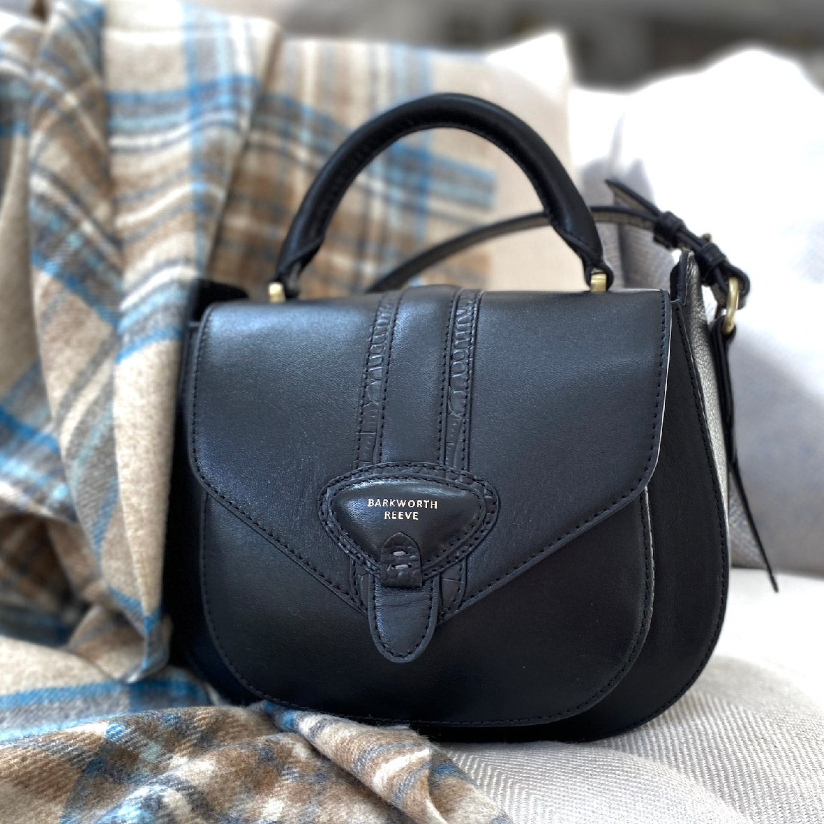 Black handbag with 'Barkworth Reeve' logo on a plaid fabric background