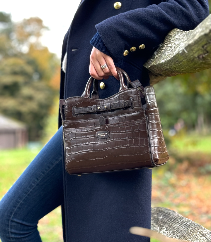 brown croc leather bag being held by a woman in a woodland setting 