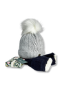A light gray cable-knit beanie with a large white faux-fur pom-pom, shown with navy blue mittens featuring white trim and a small floral gift box on a white background.