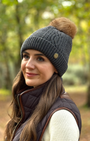 grey cable kit bobble hat with pom worn by pretty girl in a sprig woodland 