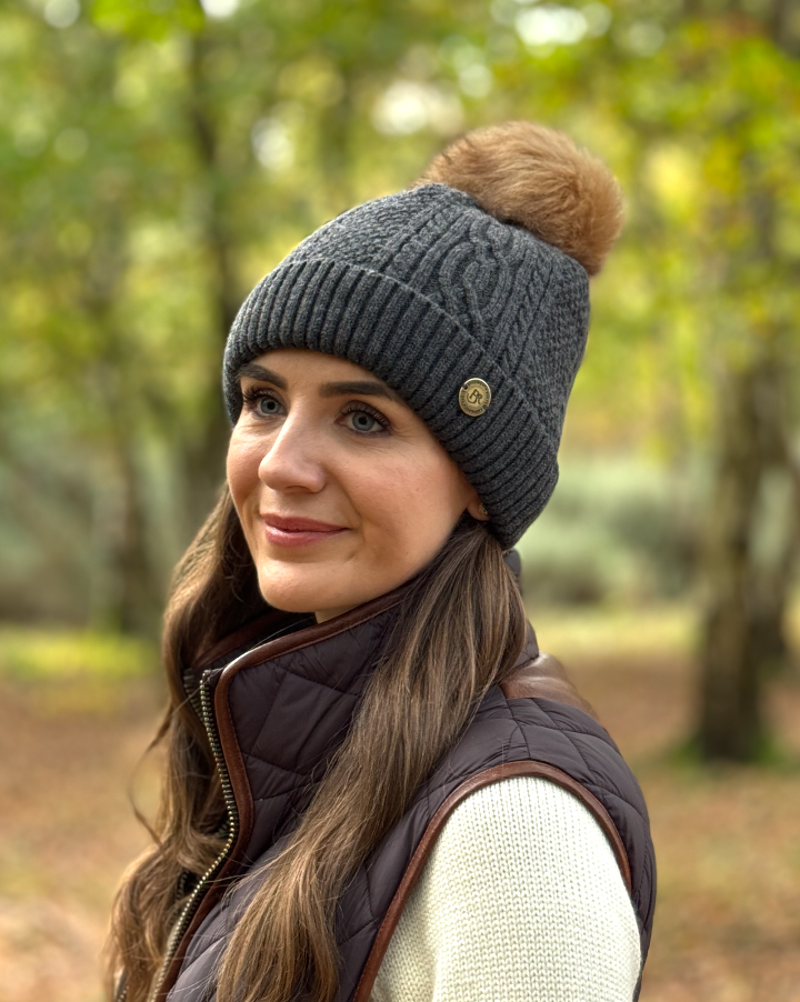 grey cable kit bobble hat with pom worn by pretty girl in a sprig woodland 