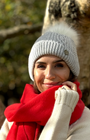 lady smiling wearing grey bobble hat with red scarf in an autumn wood 