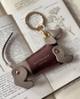 grey abd dark pink sausage dog keyring laid on a book