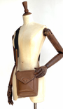 tan cross body bag on a mannequin with wooden arms 