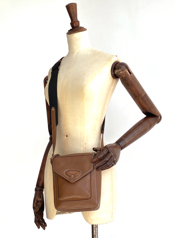 tan cross body bag on a mannequin with wooden arms 