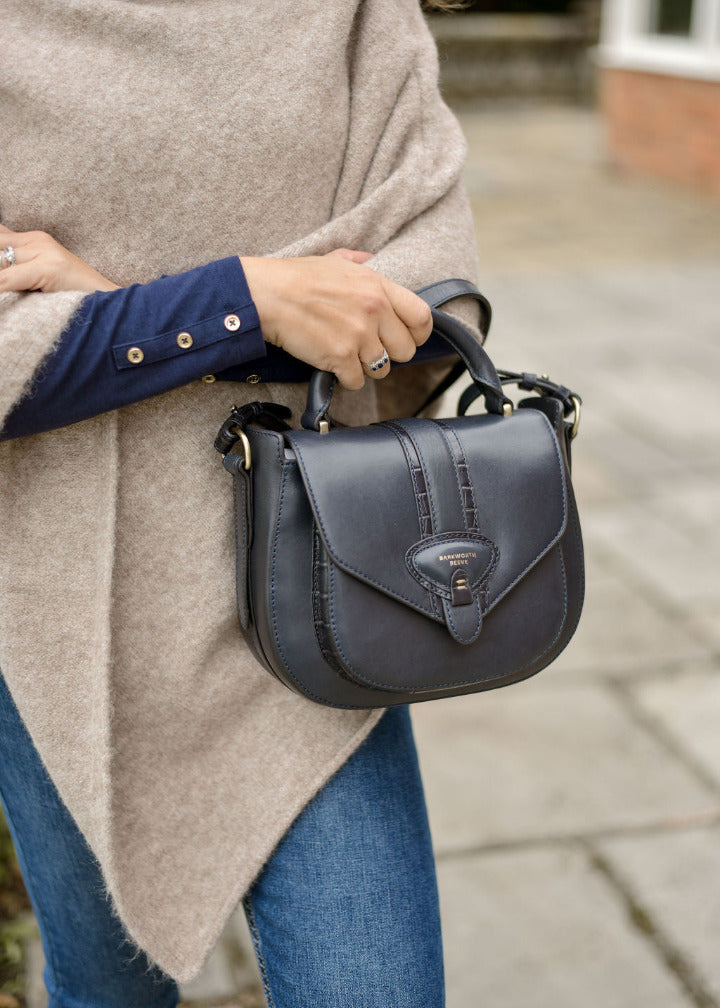 Person holding a dark blue handbag outdoors
