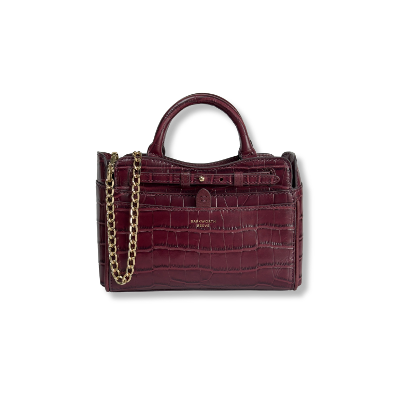A burgundy crocodile-embossed leather handbag with a top handle, gold chain strap, and gold hardware, shown on a plain white background.