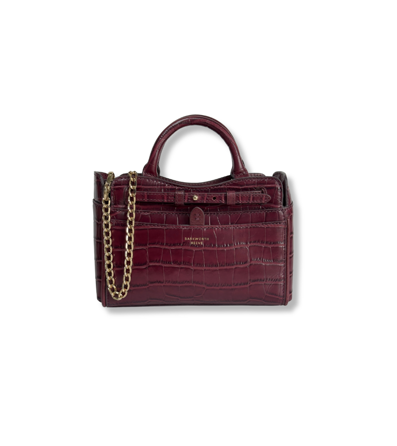 A burgundy crocodile-embossed leather handbag with a top handle, gold chain strap, and gold hardware, shown on a plain white background.