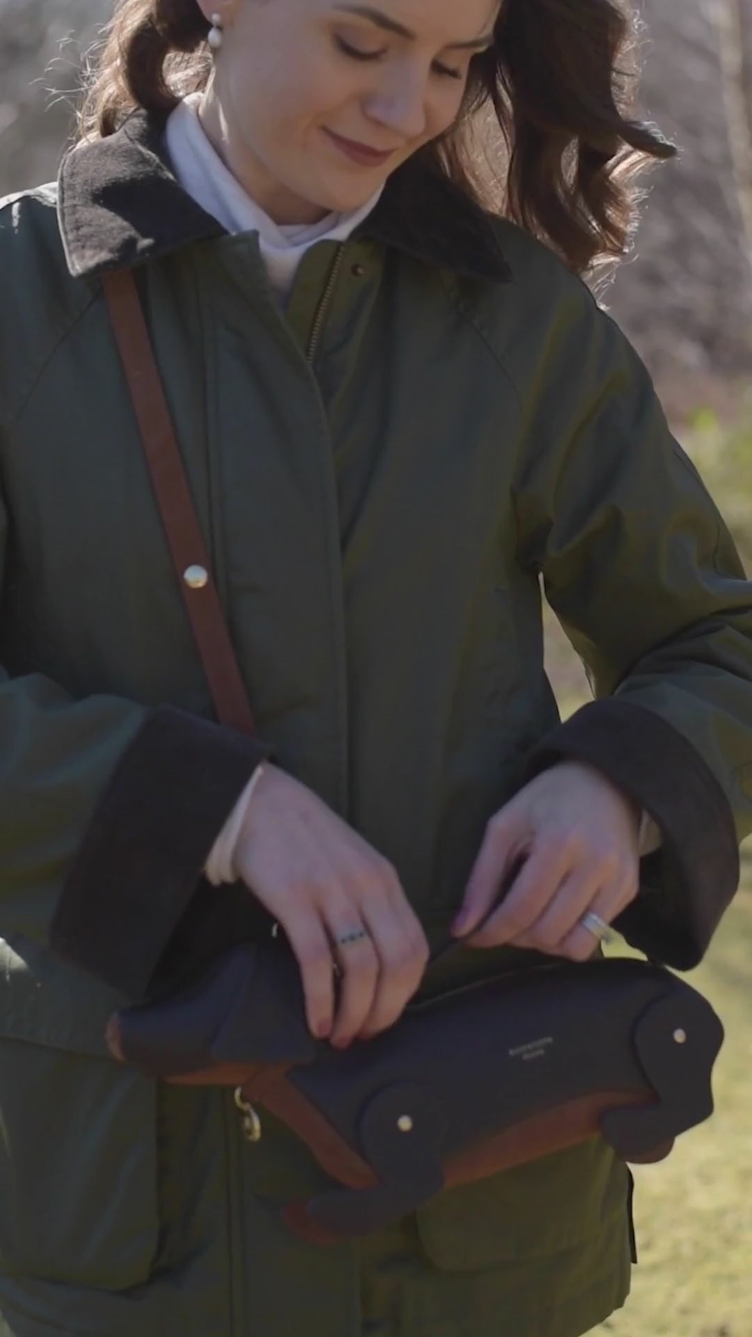 woman in the countryside on suunny day with sausage dog handbag 