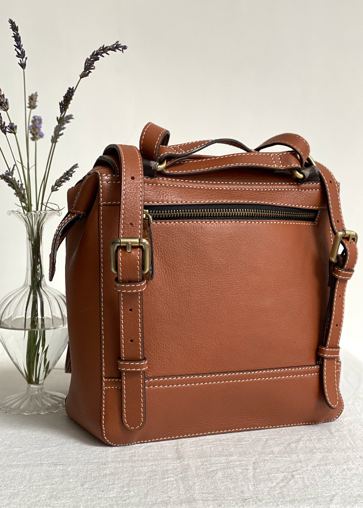 brown leather rucksack from the back with some lavender 