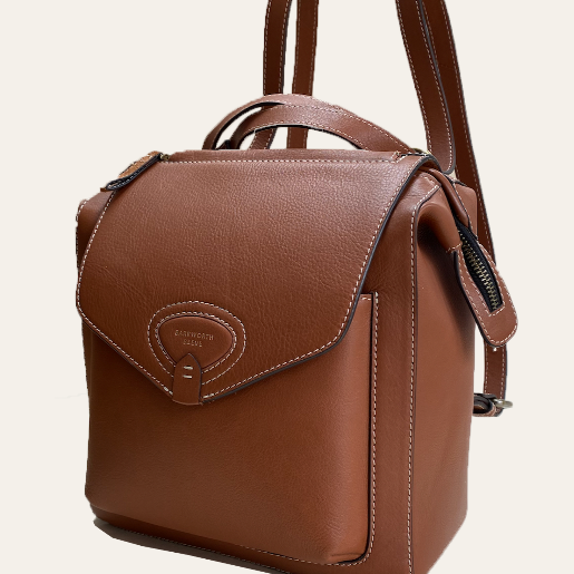 A tan leather rucksack with adjustable shoulder straps and a front flap closure.