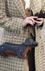 Person holding a dachshund-shaped handbag with a textured coat.