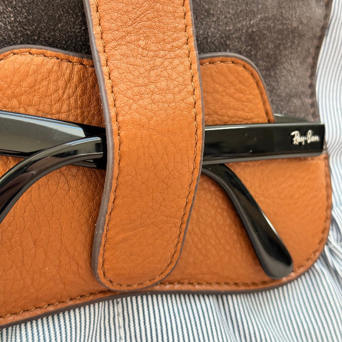 Brown leather belt with a metal buckle on a striped fabric background