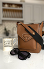 tan corss body bag on kitchen worktop with sunglasses and mug of tea