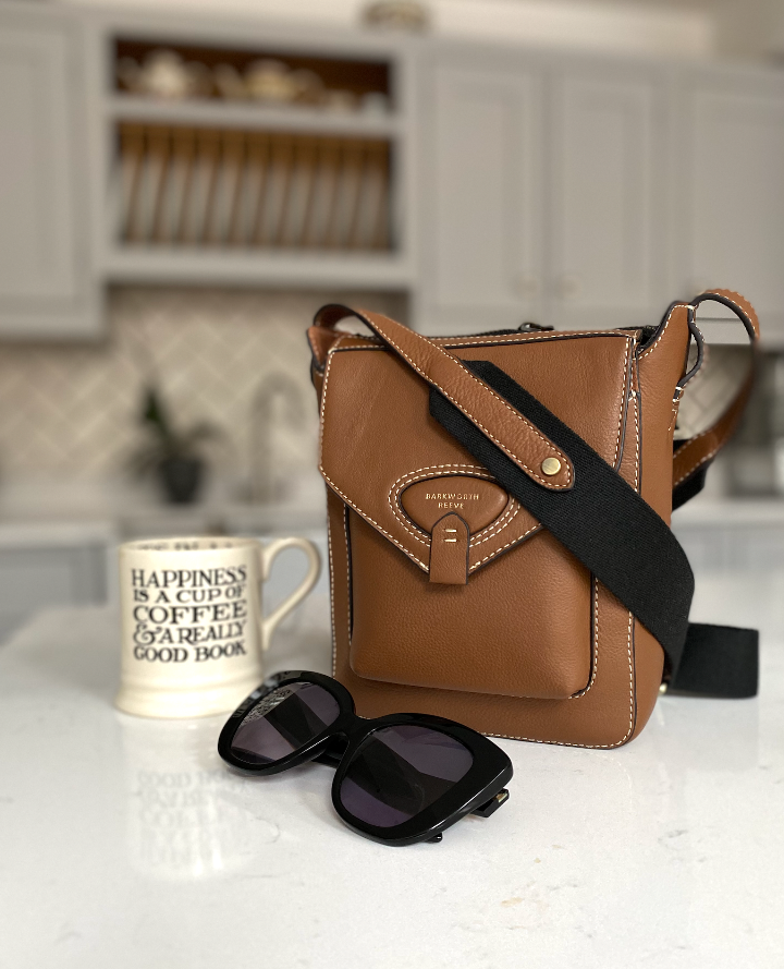 tan corss body bag on kitchen worktop with sunglasses and mug of tea
