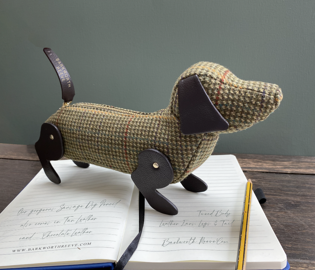 tweed sausage dog pencil case stood on top of a notebook