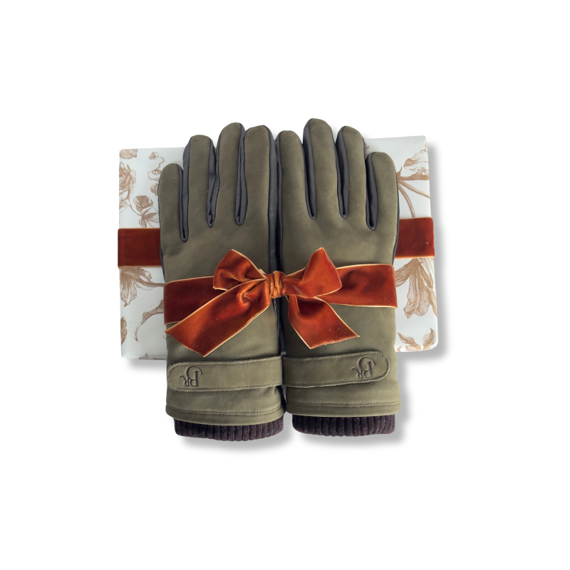 A pair of olive green winter gloves with dark gray finger panels and ribbed cuffs, tied with a rust-orange velvet bow, presented on top of a white gift box with a floral pattern.