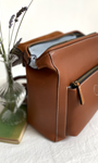 brown leather rucksack open with some flowers next to it 
